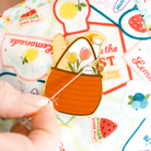 Colorful fruit-themed stickers with a hand holding a needle and thread.