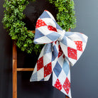 Decorative bow with red, white, and blue pattern on a wooden stool against a dark wall.