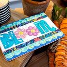 Colorful 'Bloom' sign with flowers on a wooden surface with a potted plant and decorative elements.