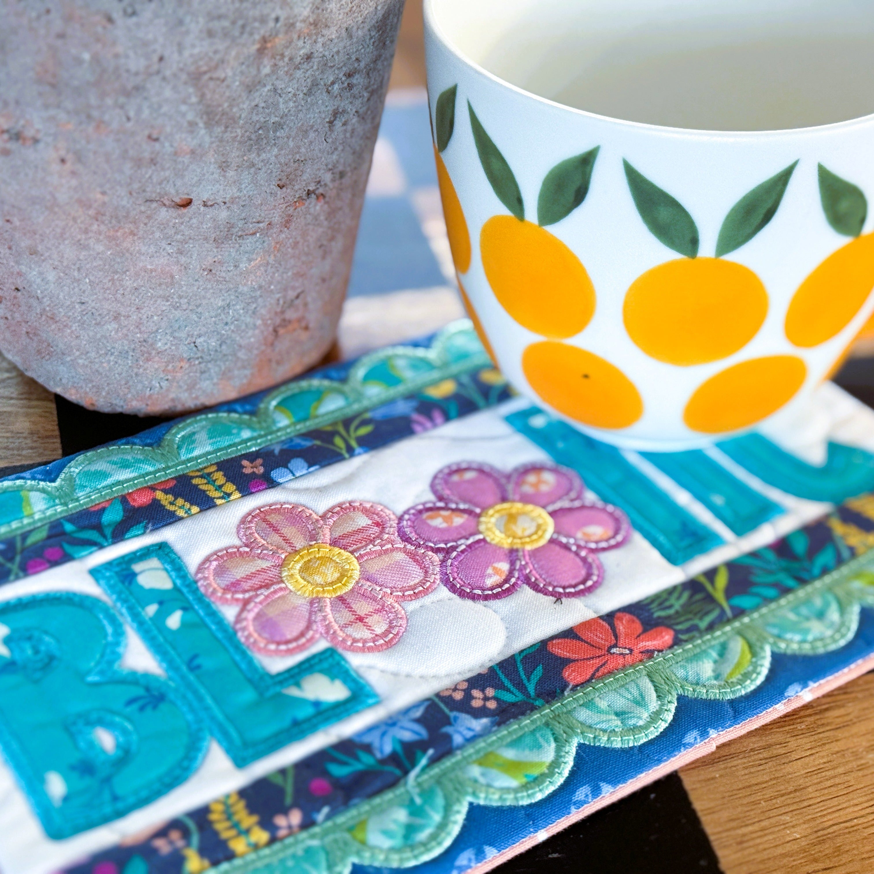 Colorful mug with floral design on a matching coaster on a wooden surface.