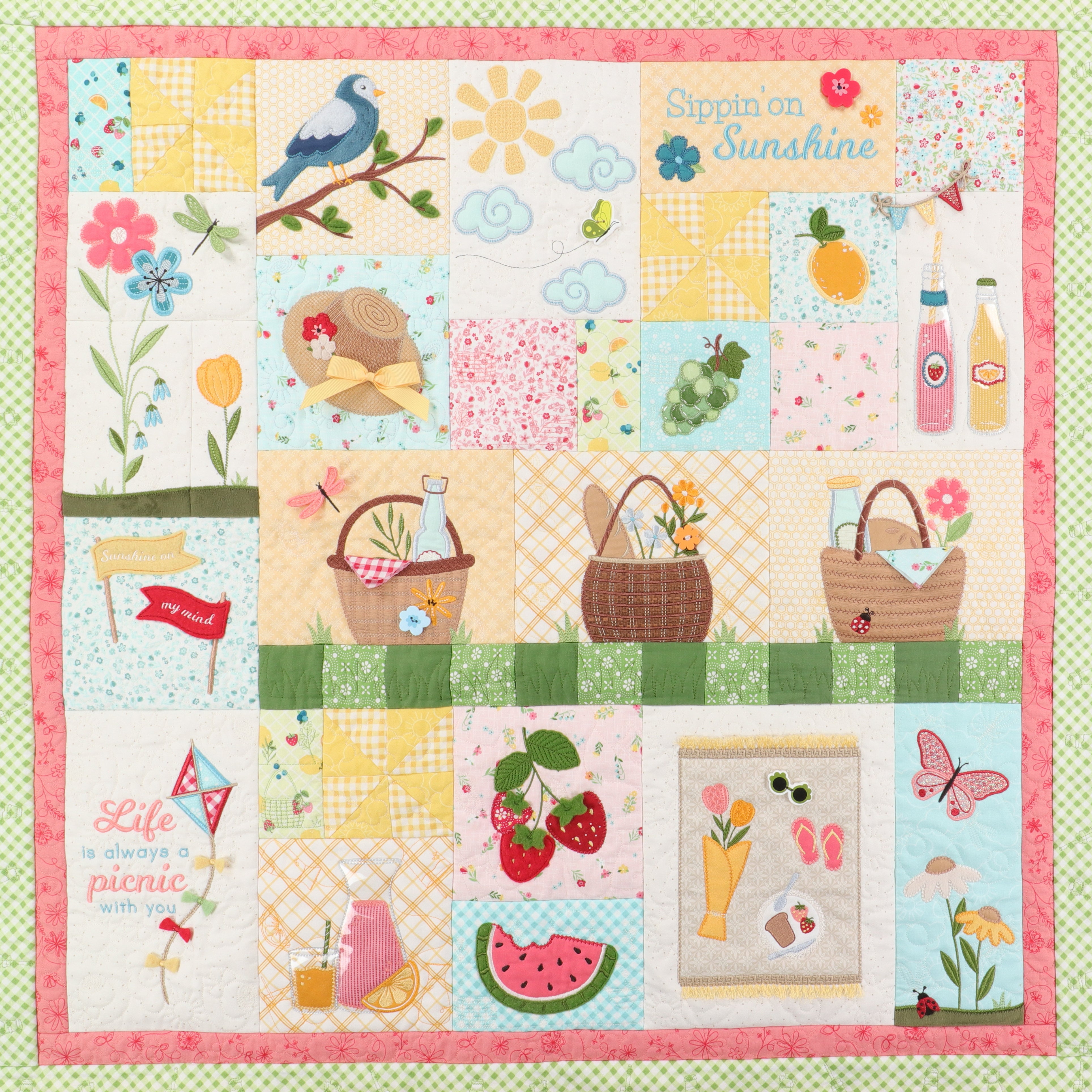 Patchwork quilt with colorful squares featuring nature and picnic-themed illustrations on a green background.