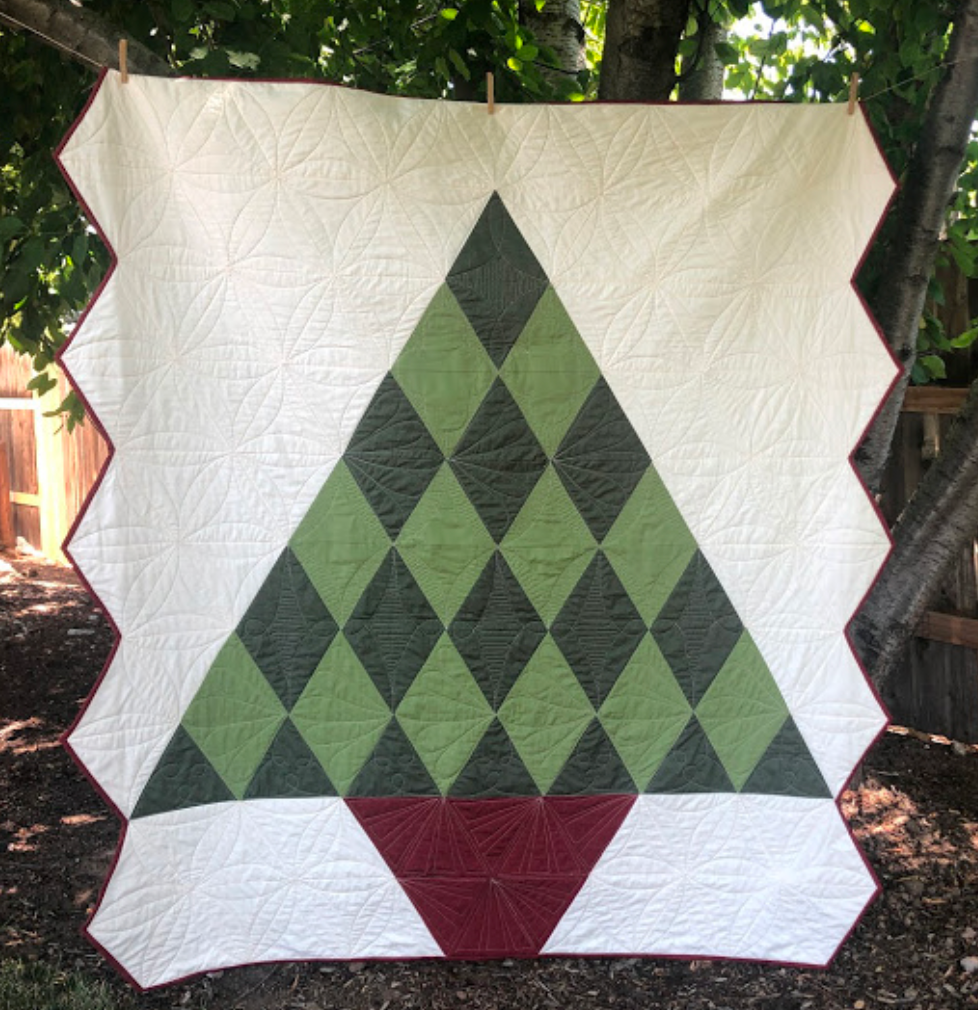 Quilt with green and red diamond pattern hanging outdoors