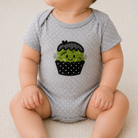 Baby wearing a gray onesie with a black and green cactus design on a white background
