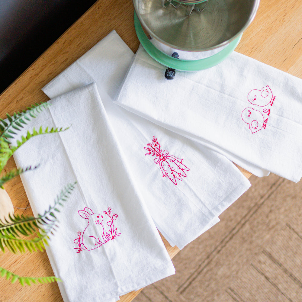 White napkins with pink rabbit designs on a wooden table.