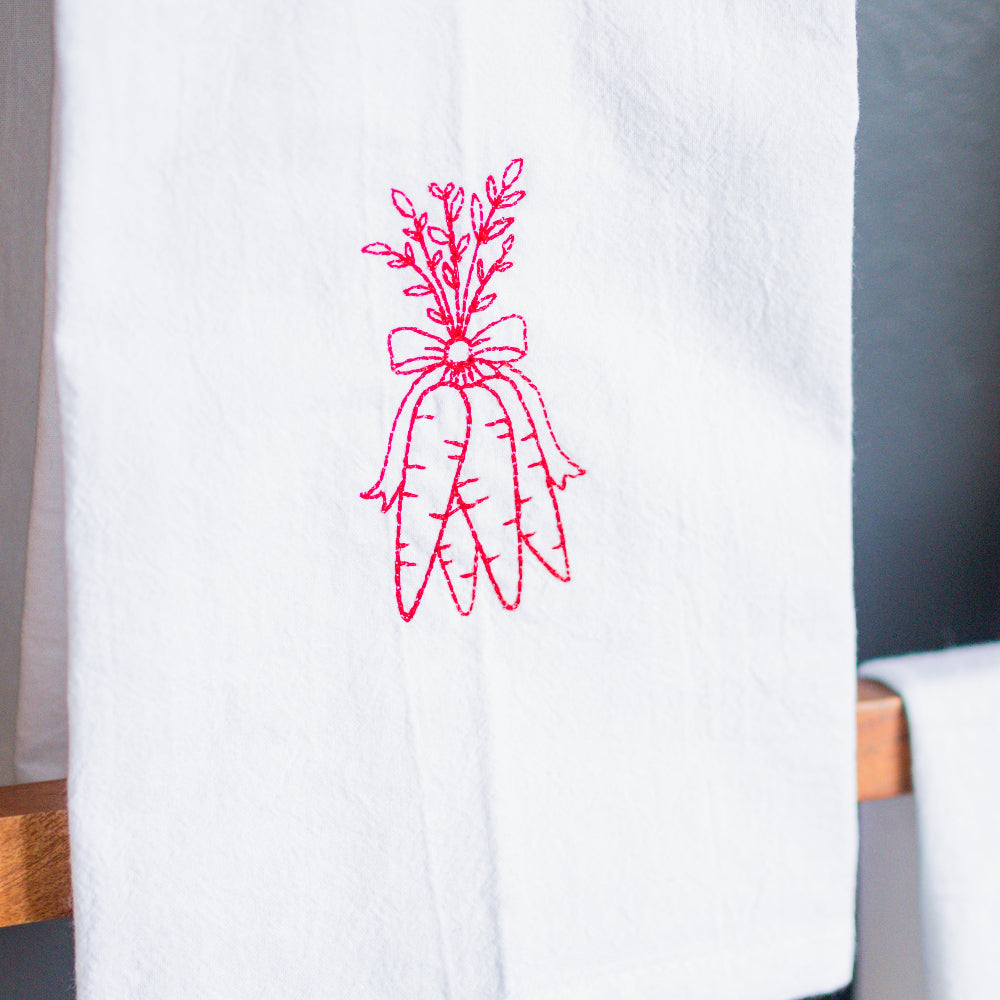 White apron with red floral embroidery on a gray background
