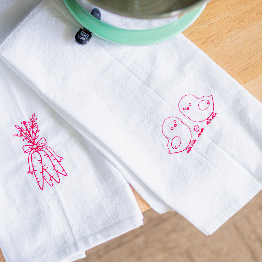 Embroidered fabric with pink floral designs on a wooden surface