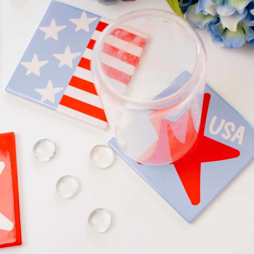 Clear plastic cups with red and white designs on a white surface with USA-themed coasters.