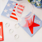 Clear plastic cups with red and white designs on a white surface with USA-themed coasters.