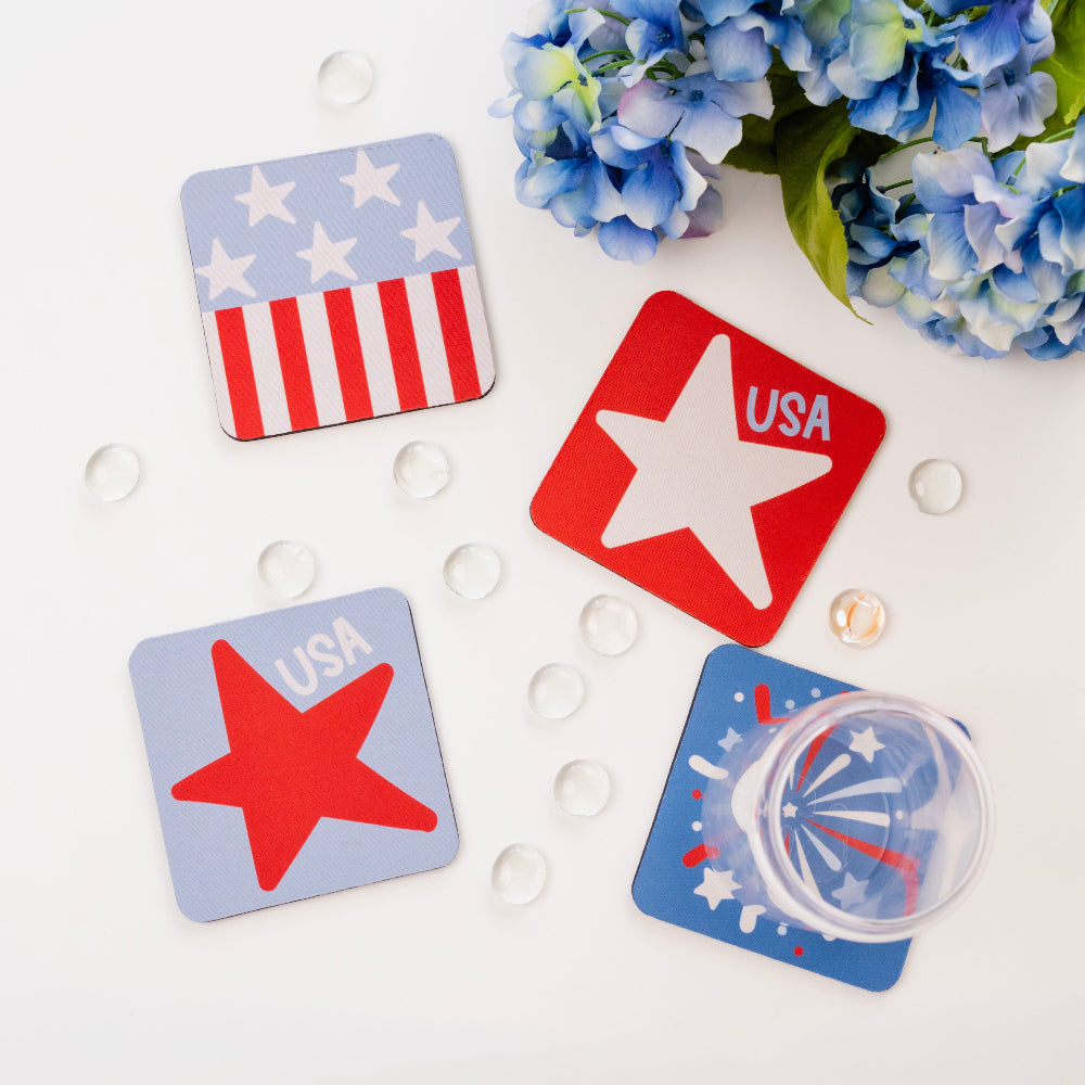 Four patriotic coasters with stars and 'USA' text on a white surface with blue flowers.