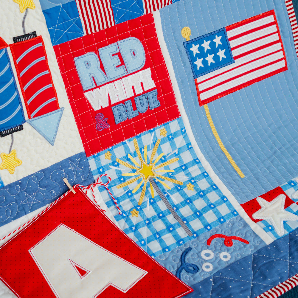 Quilt with patriotic designs including stars, flags, and fireworks.