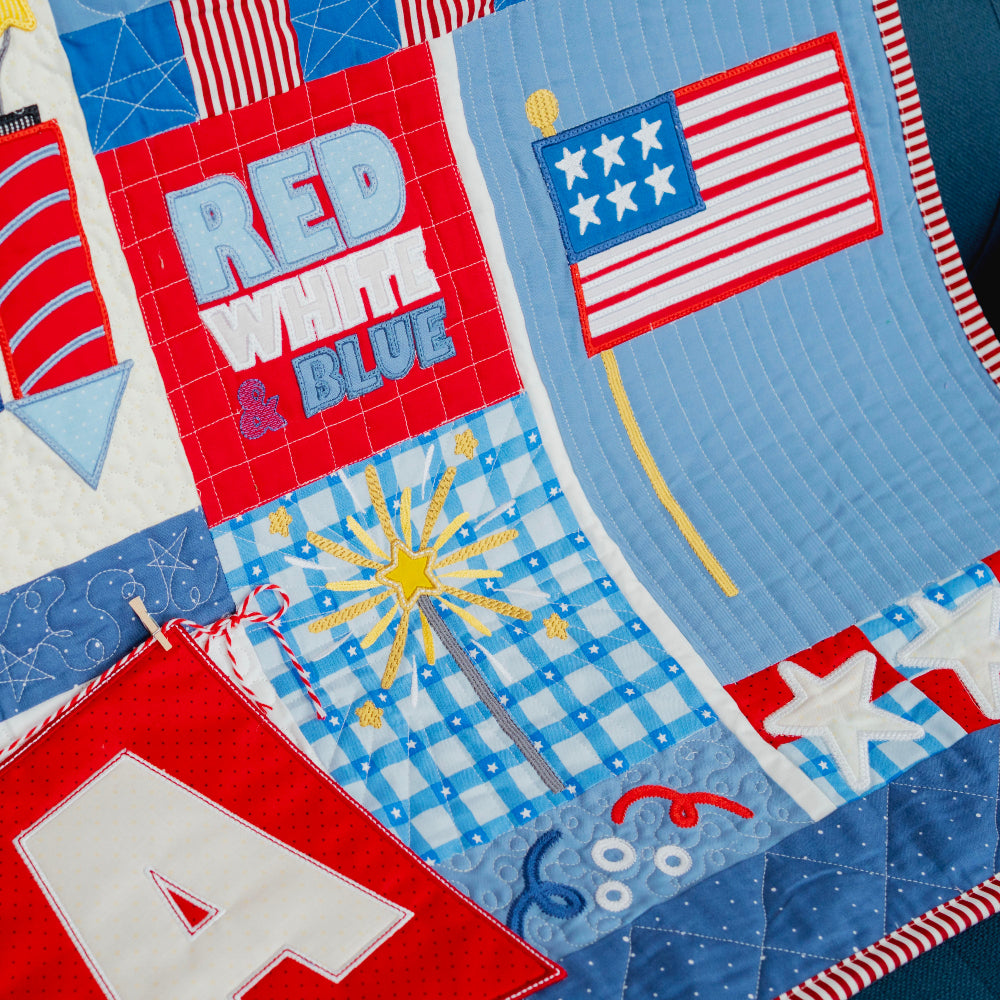 Quilt with patriotic designs including stars, flags, and fireworks.