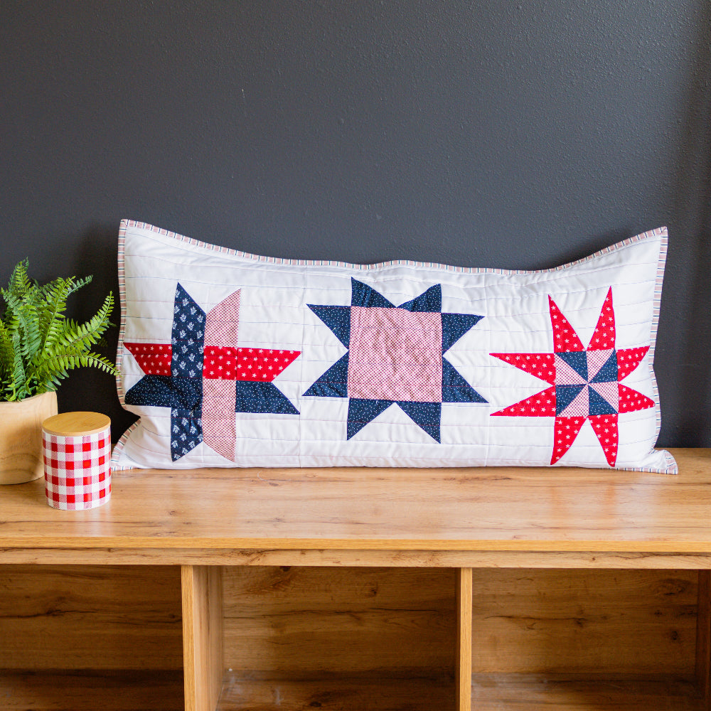 Decorative pillow with star pattern on a wooden table against a dark wall