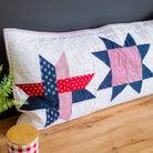 Quilt with star pattern on a wooden surface against a dark gray wall