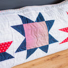 Quilt with star patterns in red, white, and blue on a wooden surface.