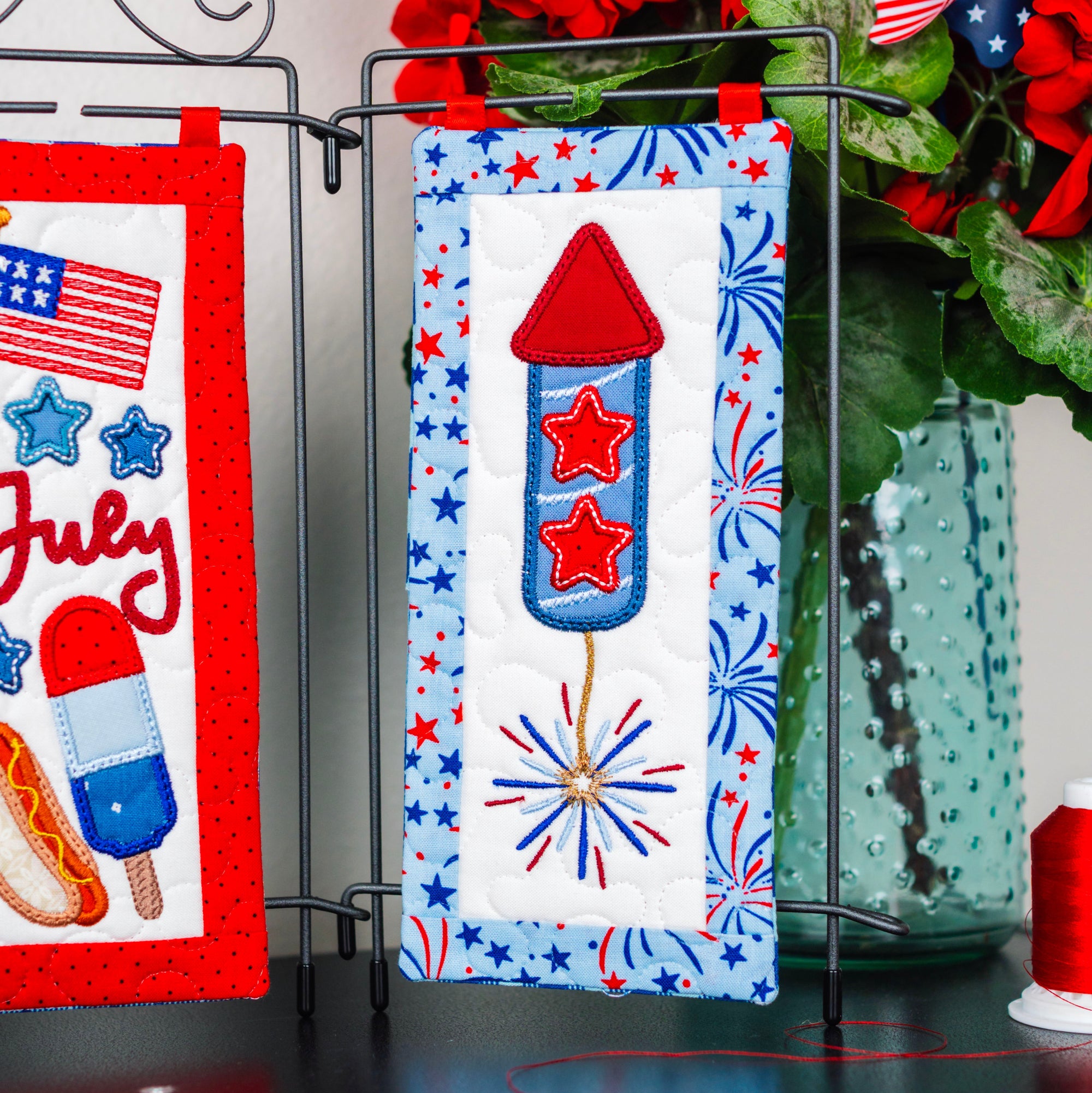 Decorative items with July 4th theme including a rocket, stars, and fireworks on a stand.