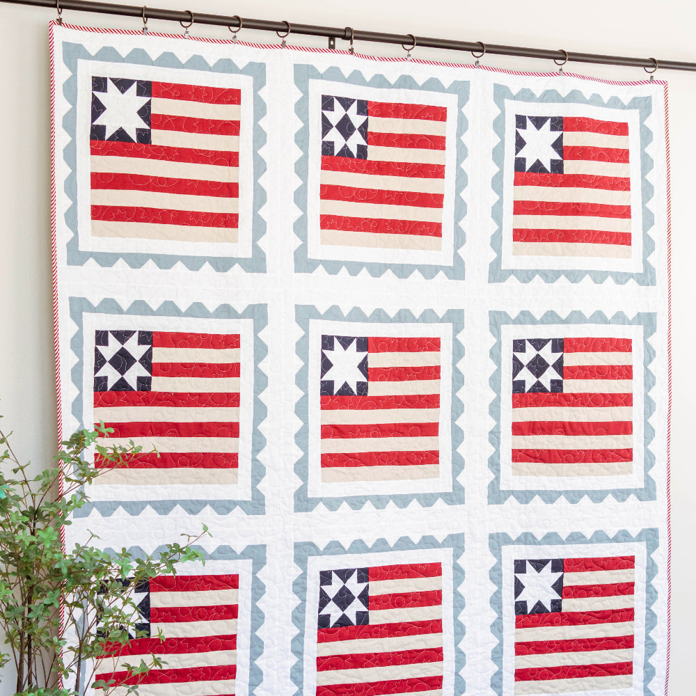 Quilt with American flag pattern hanging on a wall in a room.