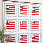 Quilt with American flag pattern hanging on a wall in a room.
