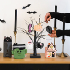 Person decorating a Halloween-themed table with various small decorative items.