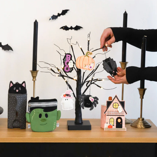 Person decorating a Halloween-themed table with various small decorative items.