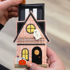 Halloween-themed house keychain with ghost and pumpkin held by a hand.