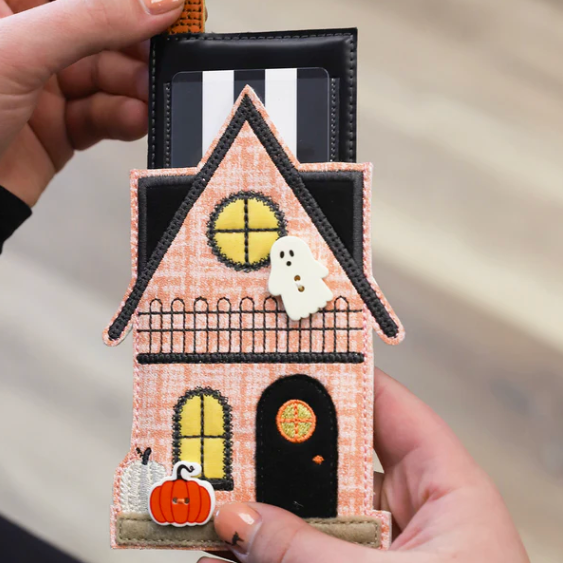 Halloween-themed house keychain with ghost and pumpkin held by a hand.