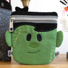 Green character-shaped pouch with a zipper on a wooden surface