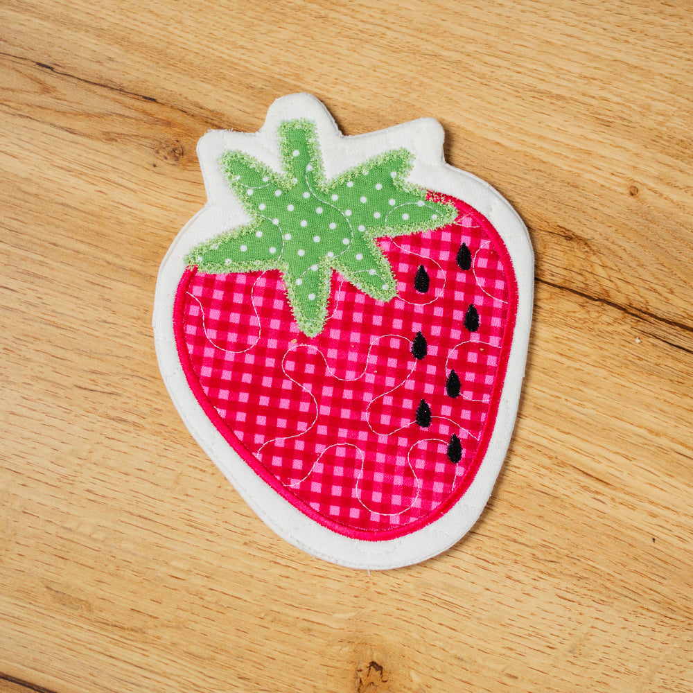 Fabric patch shaped like a strawberry on a wooden surface