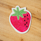 Fabric patch shaped like a strawberry on a wooden surface