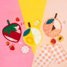 Fruit-themed coasters on a colorful background with checkered fabric.