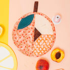 Decorative peach-shaped pot holder with a lemon and peach on a pink background
