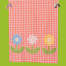 Red and white checkered fabric with colorful flower appliqués on a green background