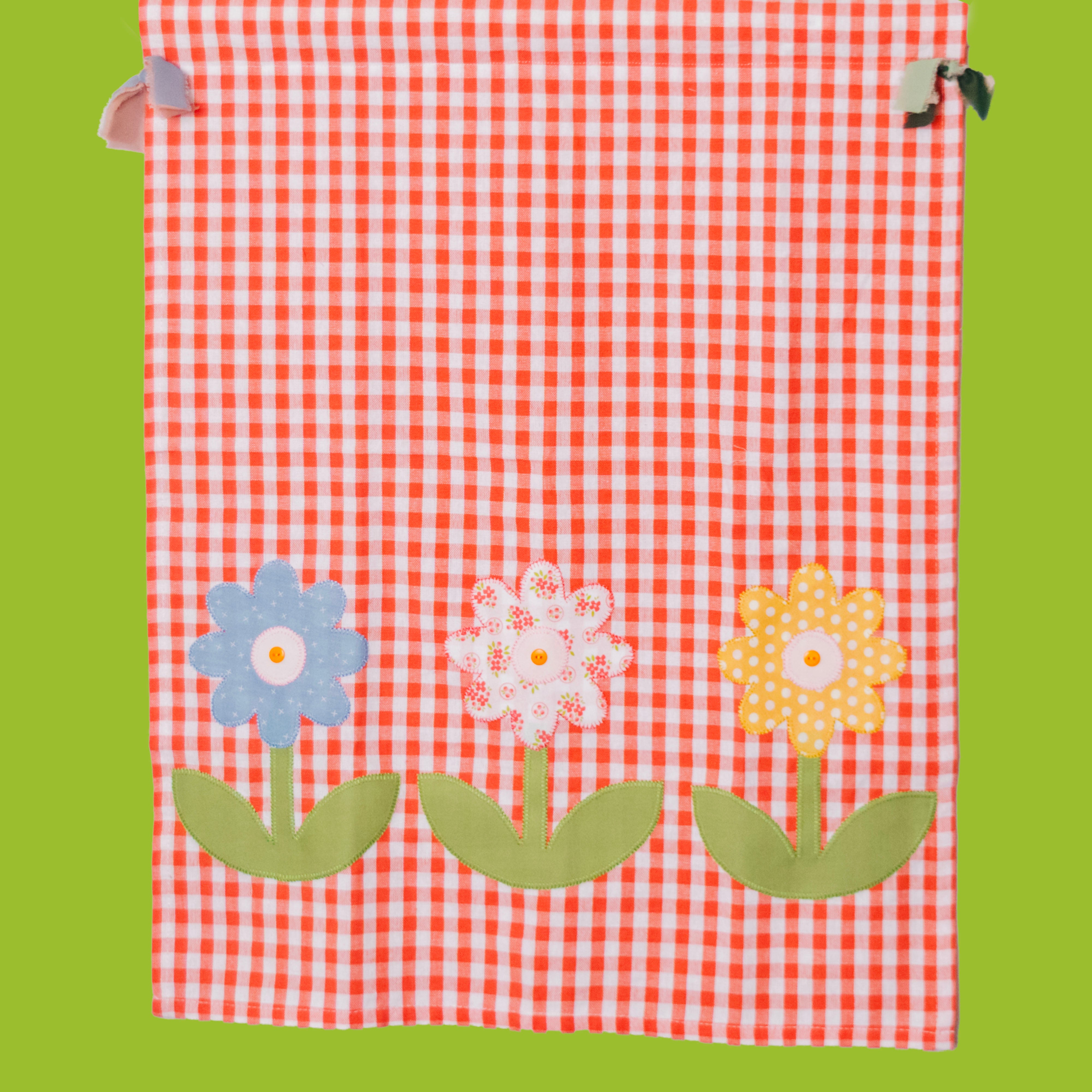 Red and white checkered fabric with colorful flower appliqués on a green background