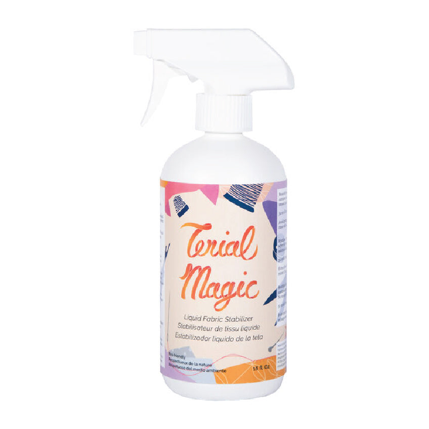 A white plastic spray bottle of Trial Magic Liquid Fabric Stabilizer with a white trigger spray top and a colorful label featuring orange and purple text.
