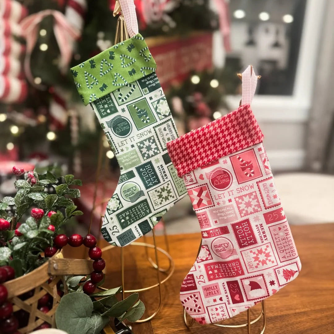 Two Christmas stockings hanging, one green with white patterns and one red with white patterns, against a festive background with decorations.