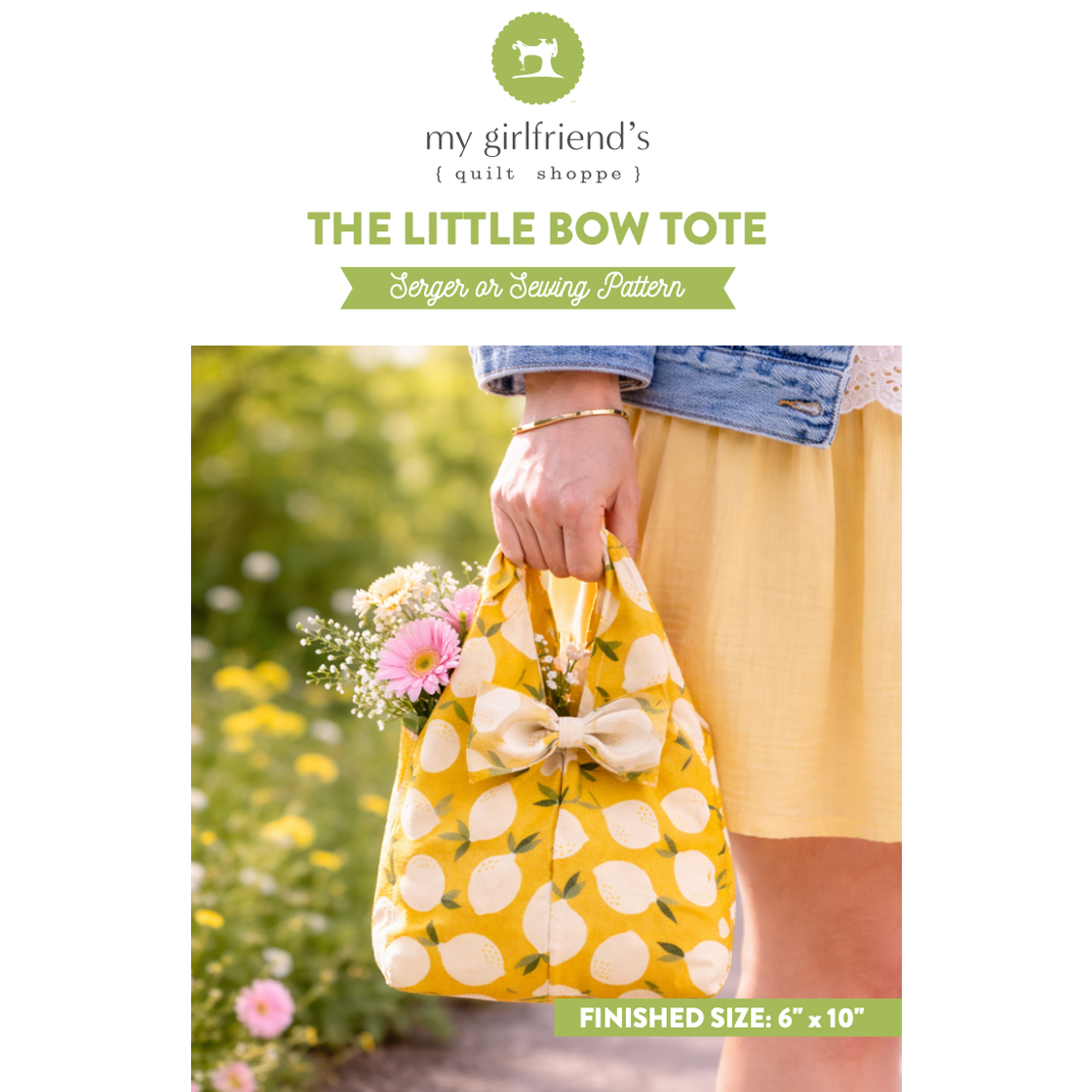 Yellow tote bag with a bow held by a person in a garden setting, featuring 'my girlfriend's quilt shoppe' branding.