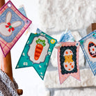 Colorful Easter-themed fabric banners hanging on a wooden chair.