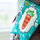 Fabric bookmark with carrot design attached to a knitted item