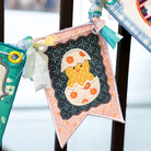 Decorative banner with a teddy bear design hanging on a black metal railing.