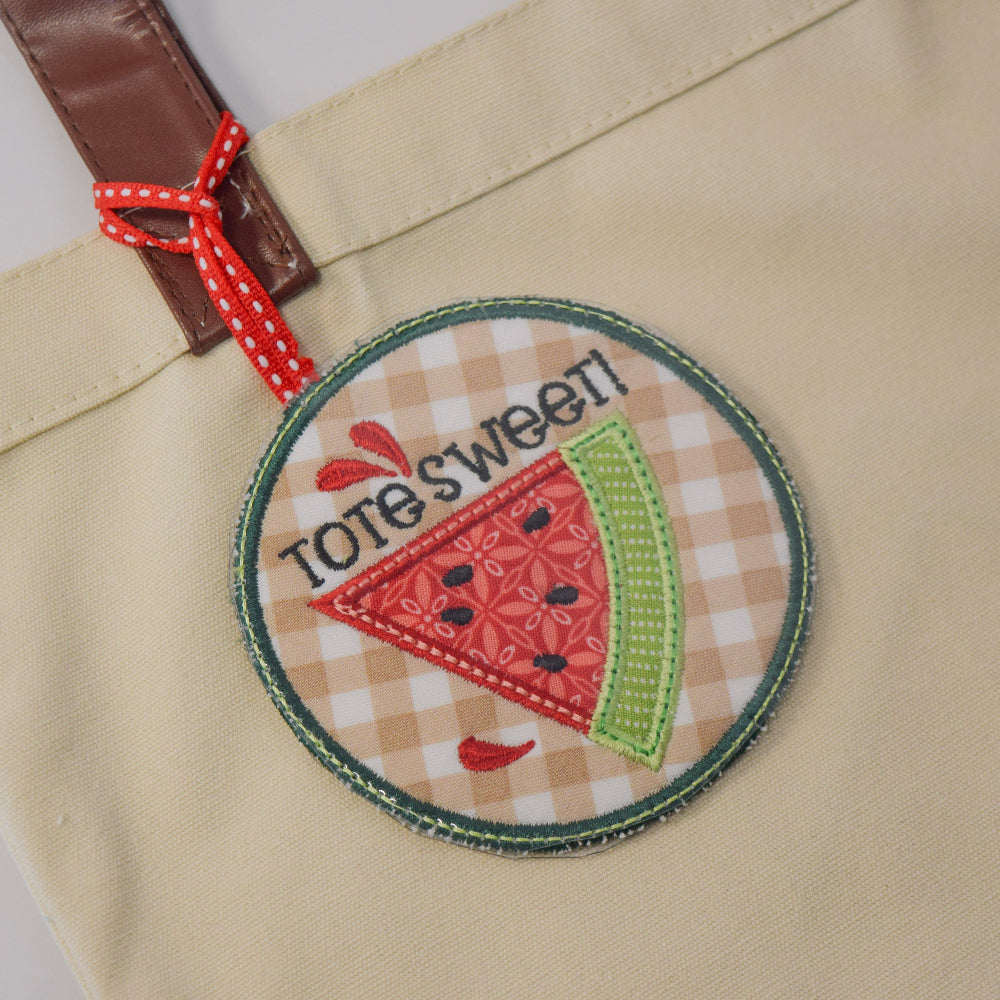 Beige bag with a decorative patch featuring a watermelon slice and text on a white background
