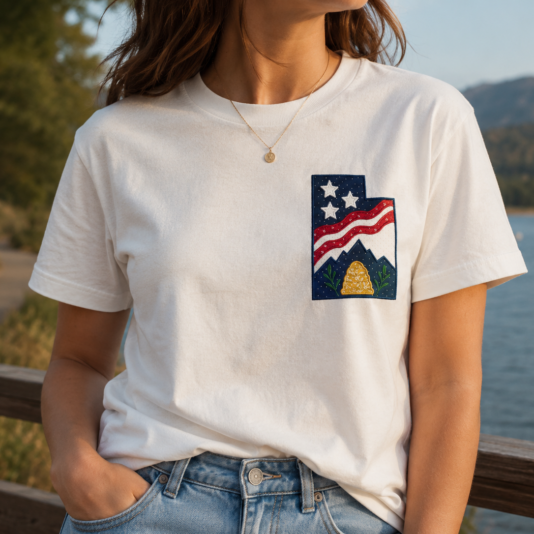 Person wearing a white t-shirt with a graphic design by a lake
