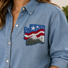 Blue denim shirt with a patch of an American flag and mountains.