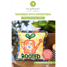 Quilt pattern cover with a colorful pillow featuring a watering can and 'Rooted' text, set against a plant and wooden surface background.