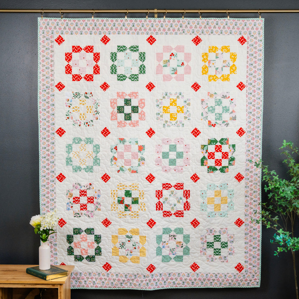 Quilt with colorful geometric patterns hanging on a wall.