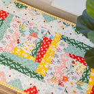 Colorful patchwork quilt on a table with a plant in the corner