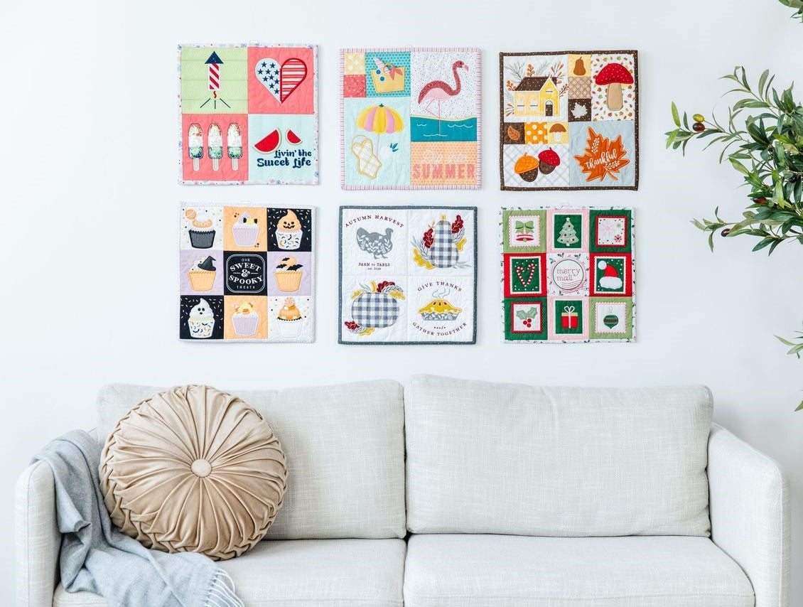 Mini Quilts Vol. 2 hanging on a wall above a couch 
