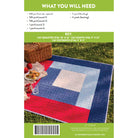 Quilt pattern book cover with quilt displayed on grass, picnic basket, and food.