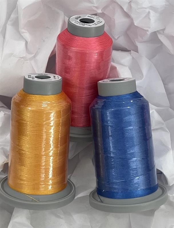 Three spools of thread in orange, pink, and blue on a white background