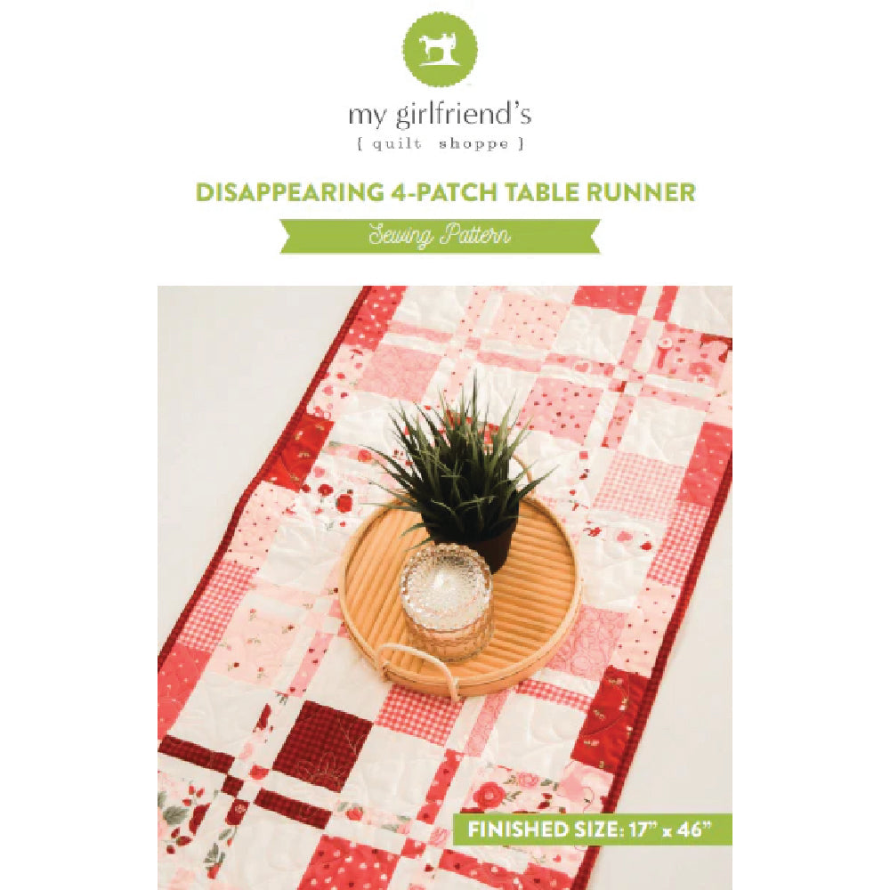 Pink and white patchwork table runner with a plant on a white background, featuring 'my girlfriend's quilt shoppe' branding.
