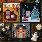 Three seasonal-themed quilts displayed on a wooden surface with autumn, winter, and Halloween decorations.