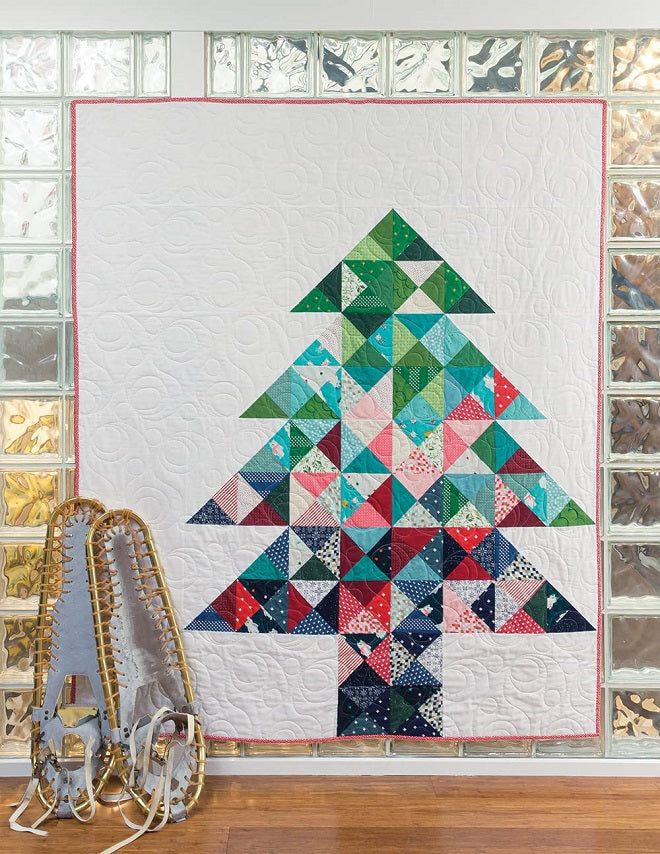 Pine tree with a white background quilt with snowshoes to the left 